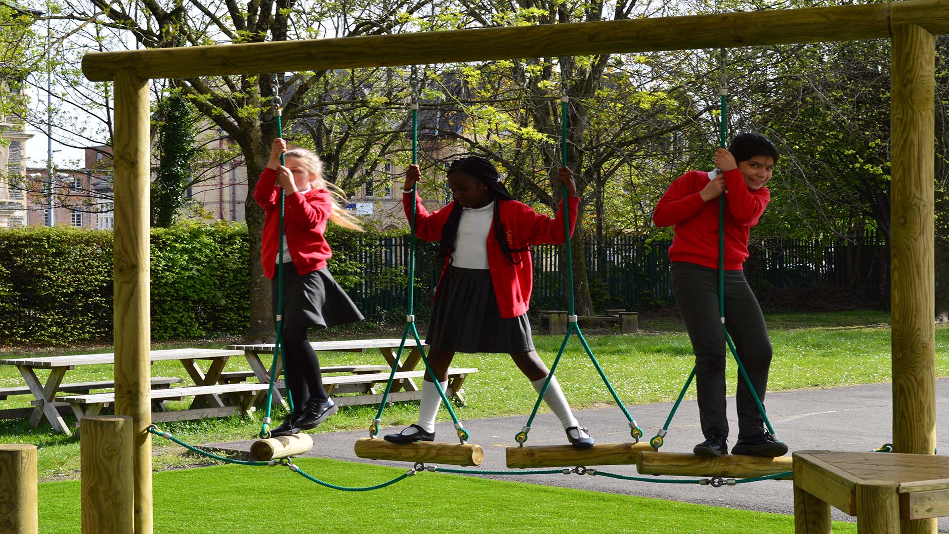 Children at St Peter's Out of School Care club in Cardiff enjoying the swings in the playground.